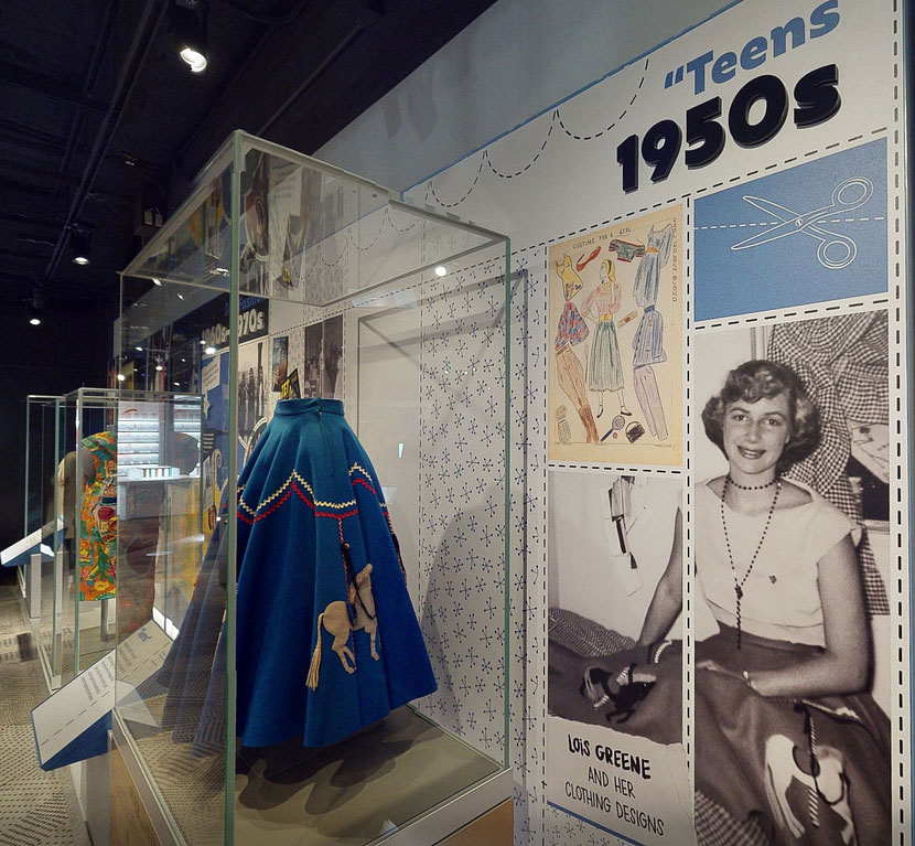 A photo of Lois (Greene) Stone featured in a Smithsonian exhibit next to intricate hand-sewn skirt.