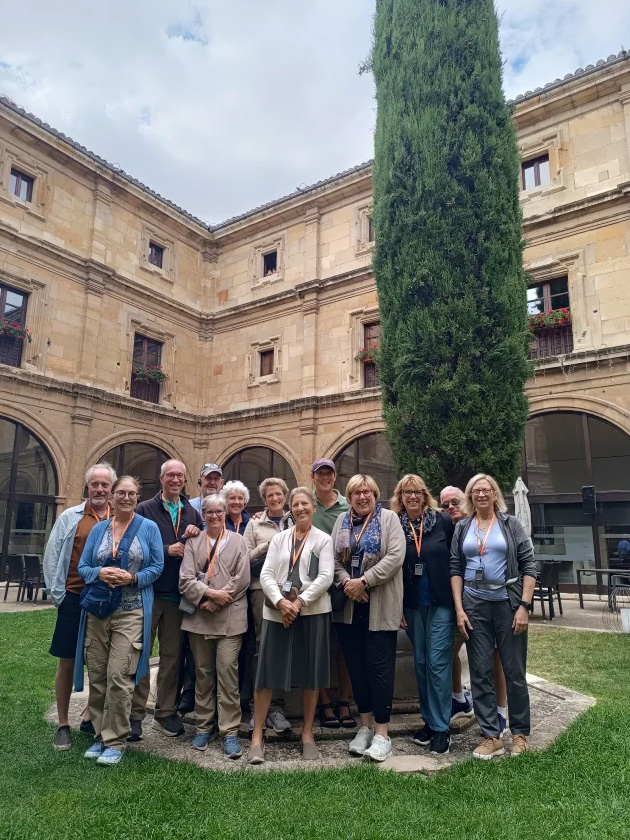 A group of men and women pose for the camera at Claustro de la basilica de San Isidoro de Leon in Spain.