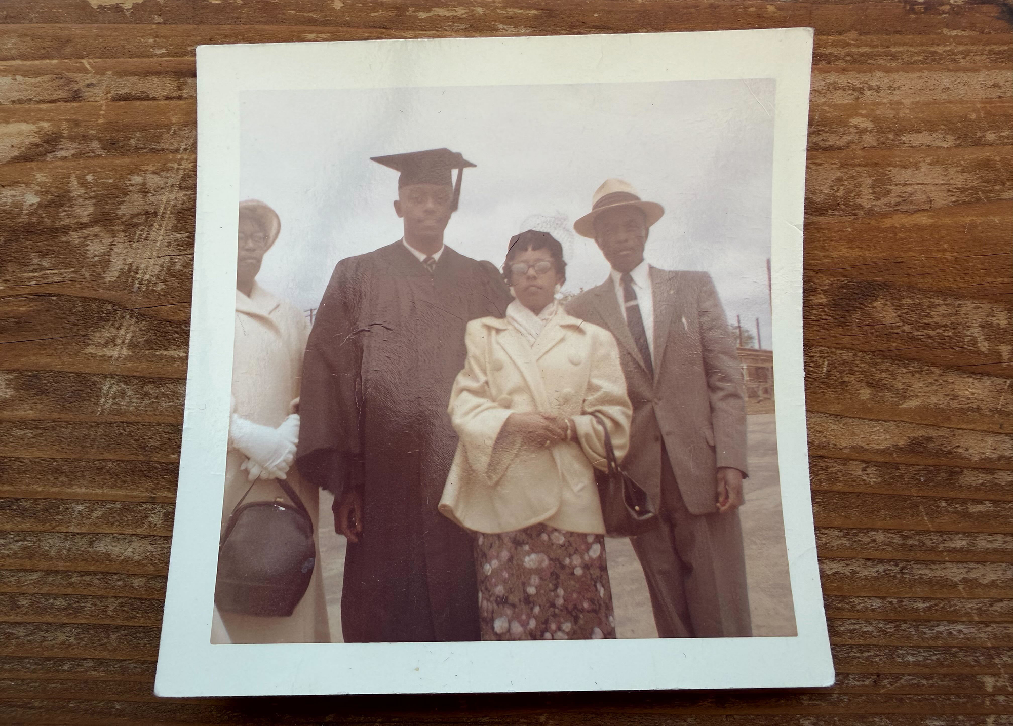 A vintage 1959 polaroid of a man and woman posing with a man in a graduation cap.