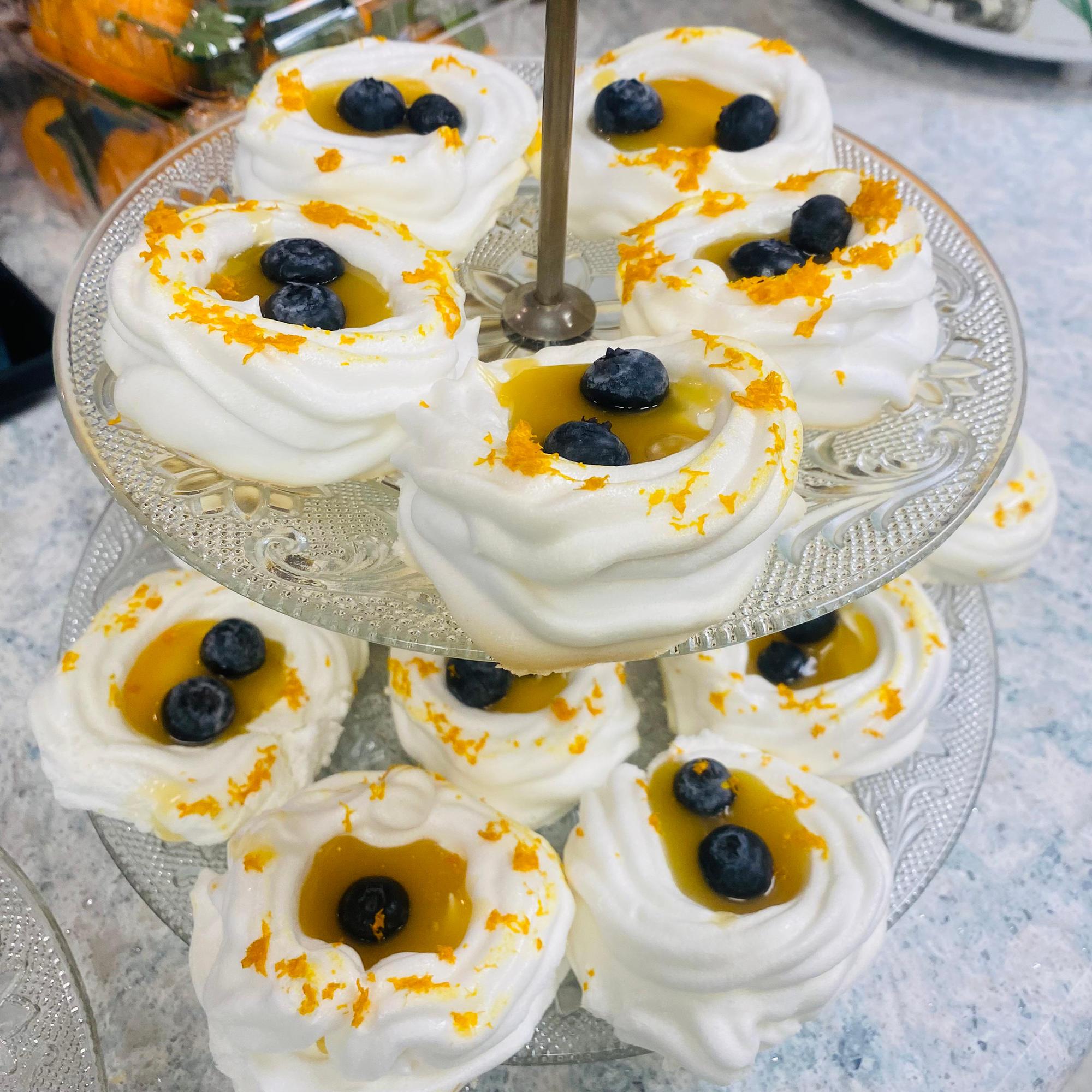 A tiered display of lemon curd pavlovas, adorned with blueberries and lemon zest.