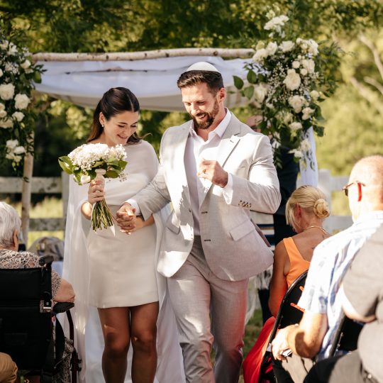 A bride and groom walk up the aisle past their guests