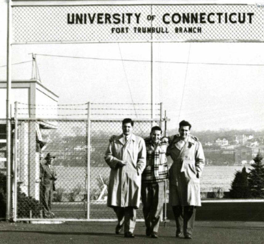 A vintage photo from the 1950s depicts three figures posing for the camera.