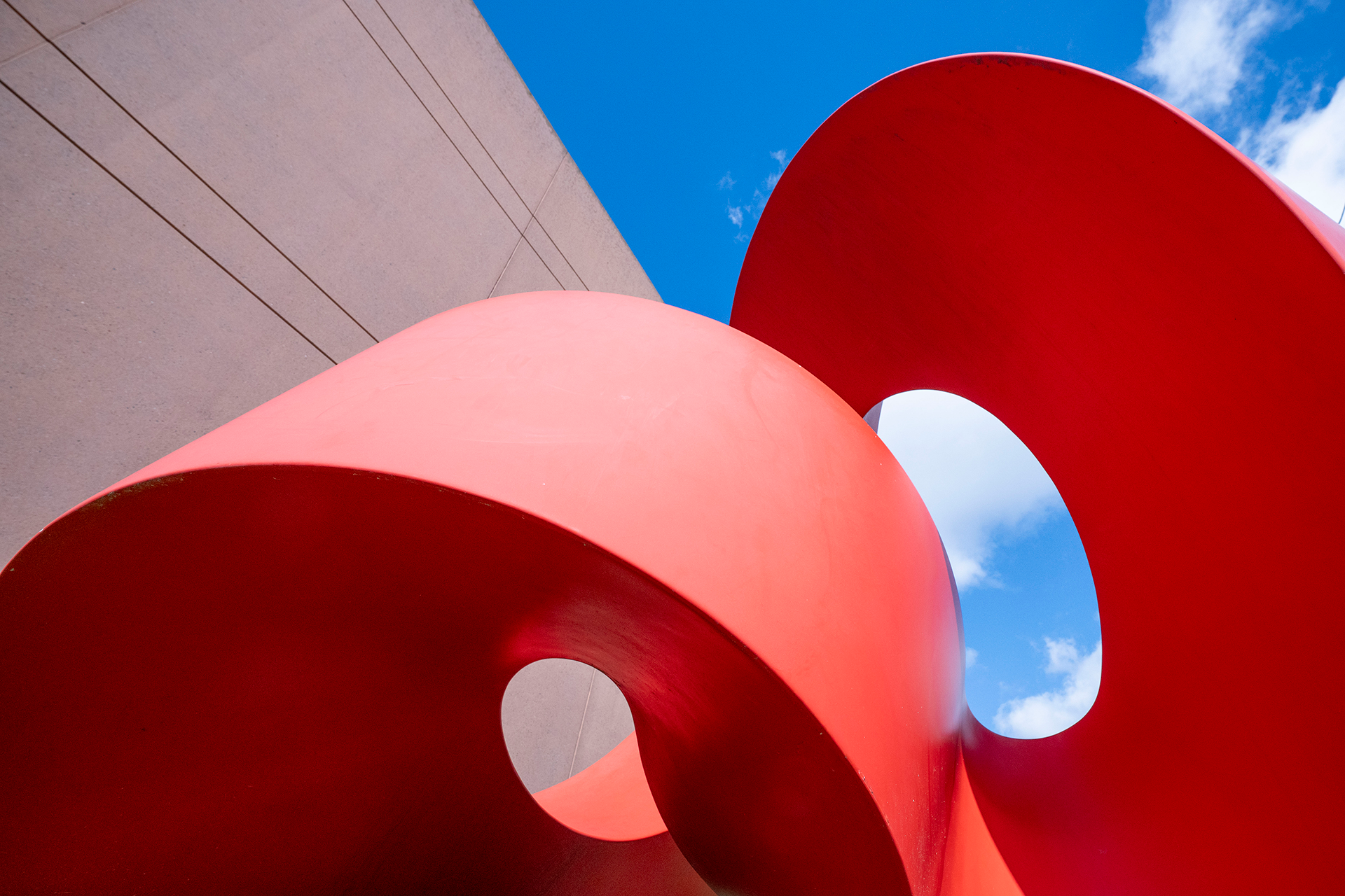 A red, swooping sculpture contrasts with the deep blue sky behind it.