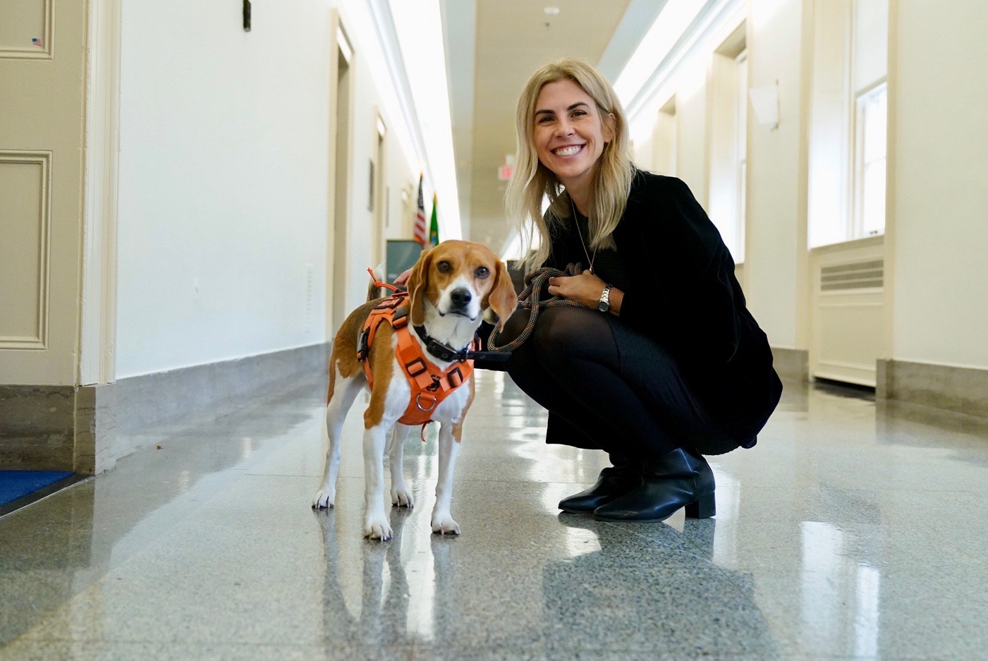 Stacy Lopresti-Goodman pets a Beagle and smiles towards the camera
