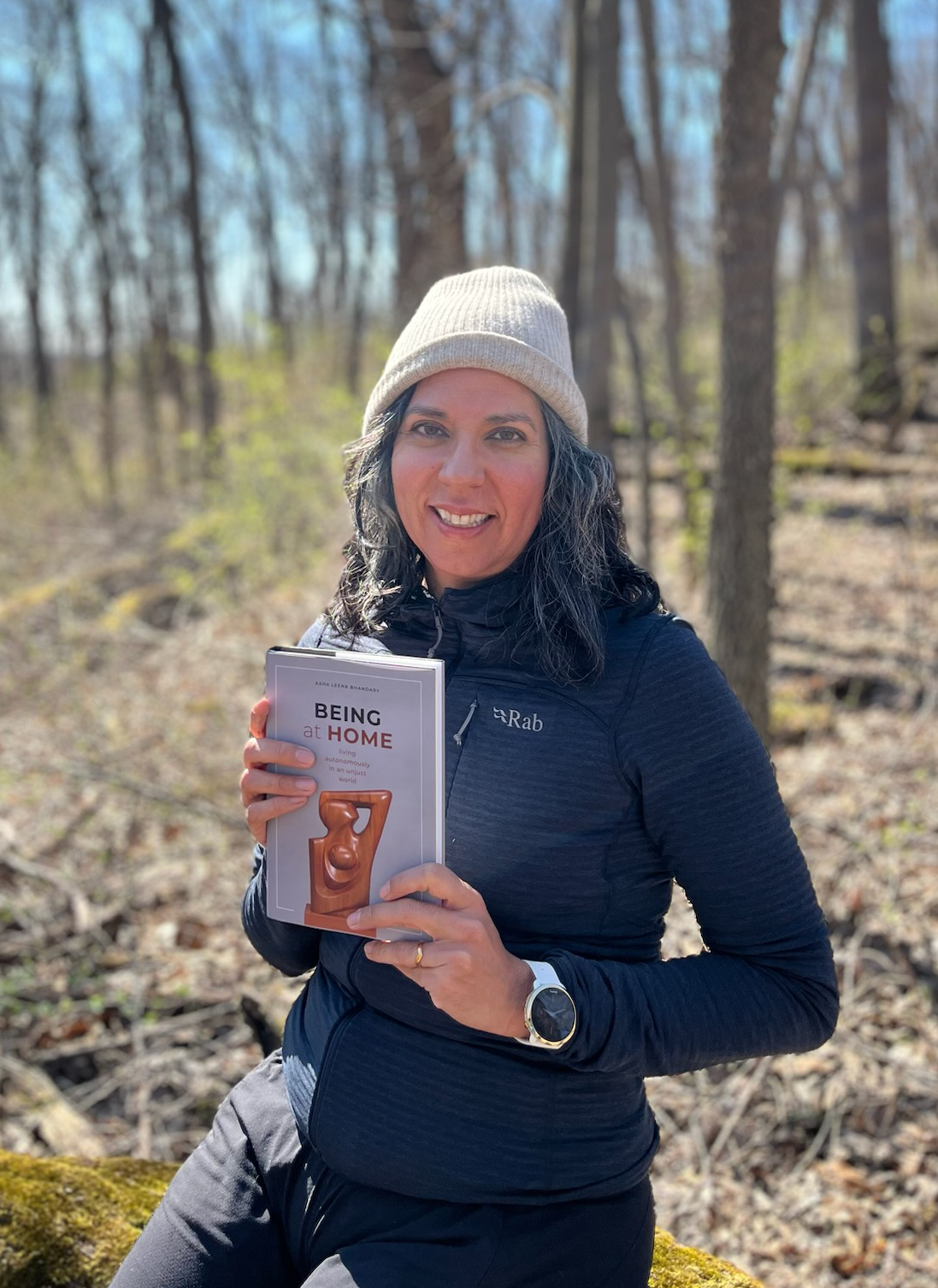 Asha Bhandary smiles and holds up a book.