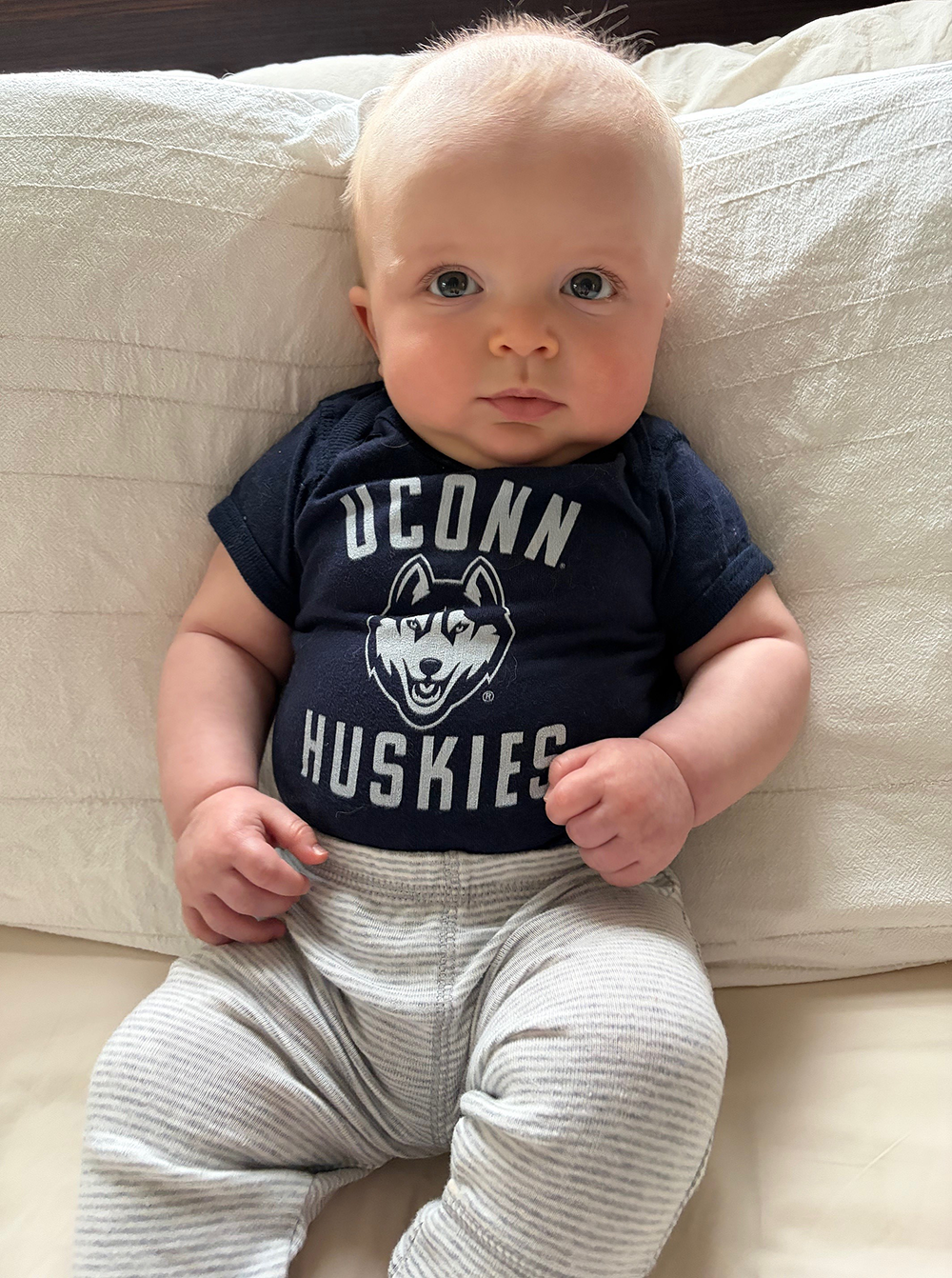 Baby boy Malcom in a UConn Huskies t-shirt.