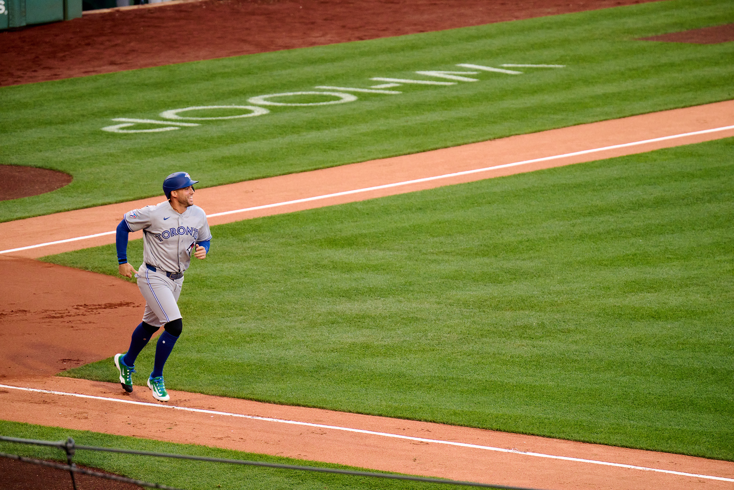 Springer runs along the field from one base to another in gray and blue Toronto uniform, smiling.