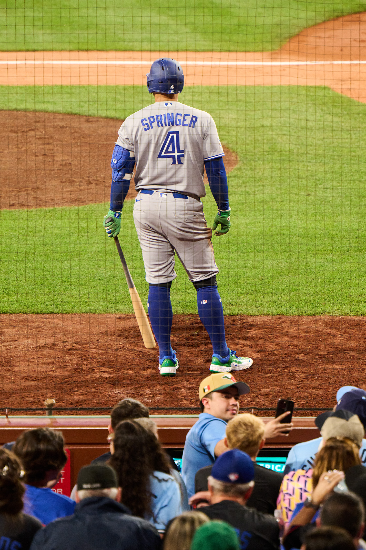 A photo of Springer, back to the viewer, standing in front of the audience. He holds a bat. His gray-and-blue uniform reads "Springer 4".